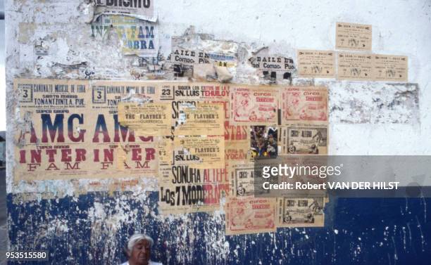 Visage d'une femme appuyée contre un mur recouvert d'affiche en septembre 1982, Mexique.