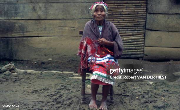 Vieille femme pieds nus assise devant sa maison en avril 1977, Mexique.