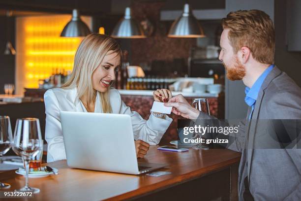 close-up of a man and woman exchanging business card in a cafe / restaurant - business cards on table stock pictures, royalty-free photos & images