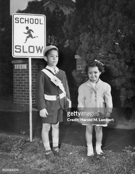 YOUNG BOY AND GIRL STANDING NEAR ROAD SIGN