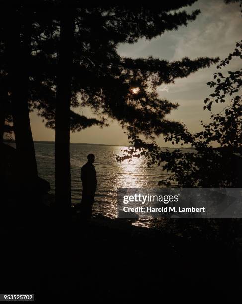 MEN STANDING NEAR LAKE AT SUNSET