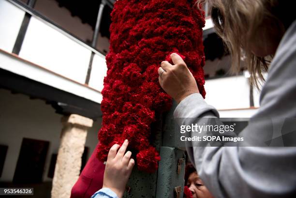 Women decorates with red carnations a cross that will be part of an altar in the "Día de la Cruz" in Granada. El día de la Cruz or Día de las Cruces...