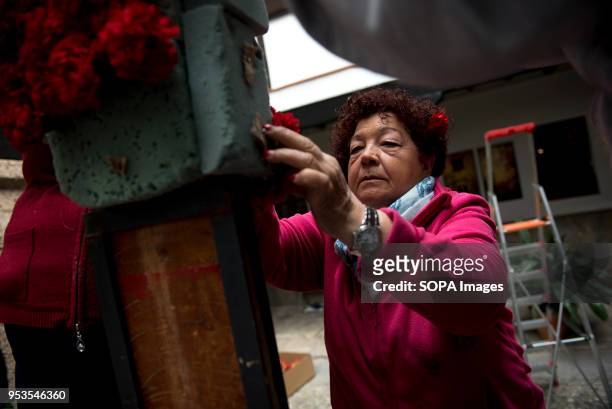 Woman decorates with red carnations a cross that will be part of an altar in the "Día de la Cruz" in Granada. El día de la Cruz or Día de las Cruces...