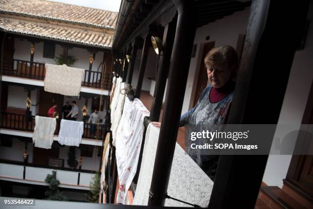 Woman decorates with a shawl the "Corrala de Santiago" for the "Dia de la Cruz". El día de la Cruz or Día de las Cruces is one of the most beautiful...