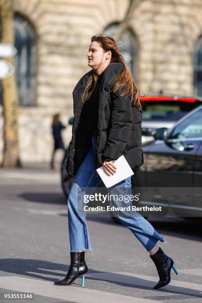Guest wears a black puffer coat, blue cropped pants, black shoes with blue heels, during Paris Fashion Week Womenswear Fall/Winter 2018/2019, on...