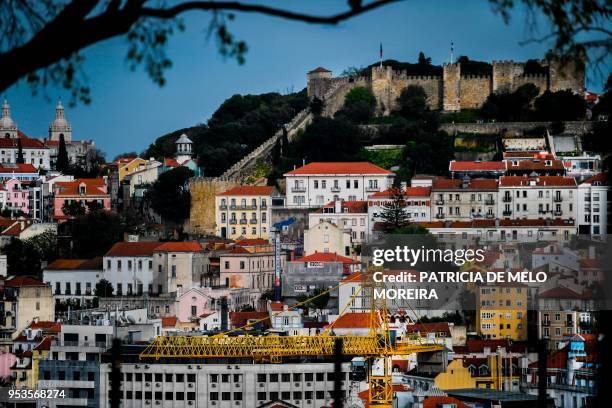 Construction crane rises in downtown Lisbon on April 19, 2018. - Lisbon's azure skies are dotted with forests of cranes as scores of construction...