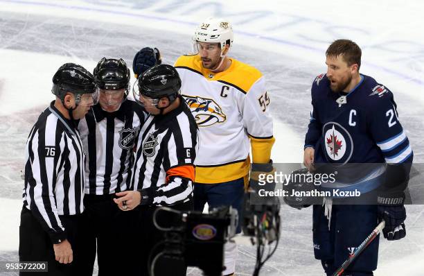 On-ice officials confer following a scrum as Roman Josi of the Nashville Predators and Blake Wheeler of the Winnipeg Jets await their call during a...