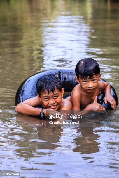 zwei kleine vietnamesische jungs baden im mekong river delta, vietnam - kinder badeboot stock-fotos und bilder