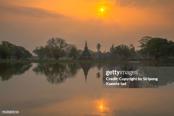the reflection of pagodas and trees at sunrise inside the sukhothai historical park, sukhothai province, thailand. - copyright by siripong kaewla iad stock pictures, royalty-free photos & images