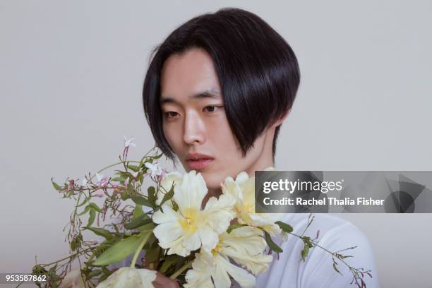 Asian young adult male holding and smelling bouquet of flowers