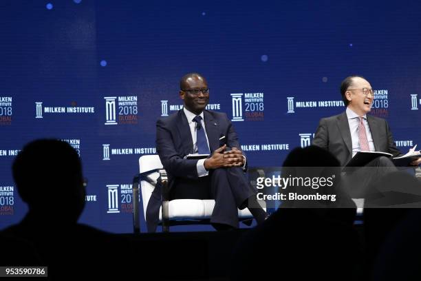 Tidjane Thiam, chief executive officer of Credit Suisse Group AG, left, and Jim Yong Kim, president of the World Bank Group, react during the Milken...