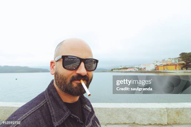 mid adult man with sunglasses and a cigarette in his mouth - glatze drogenabhängig stock-fotos und bilder