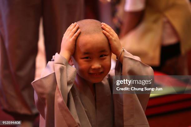 Child rubs his head after a Buddhist monk shaved his hair off during the 'Children Becoming Buddhist Monks' ceremony forthcoming buddha's birthday at...