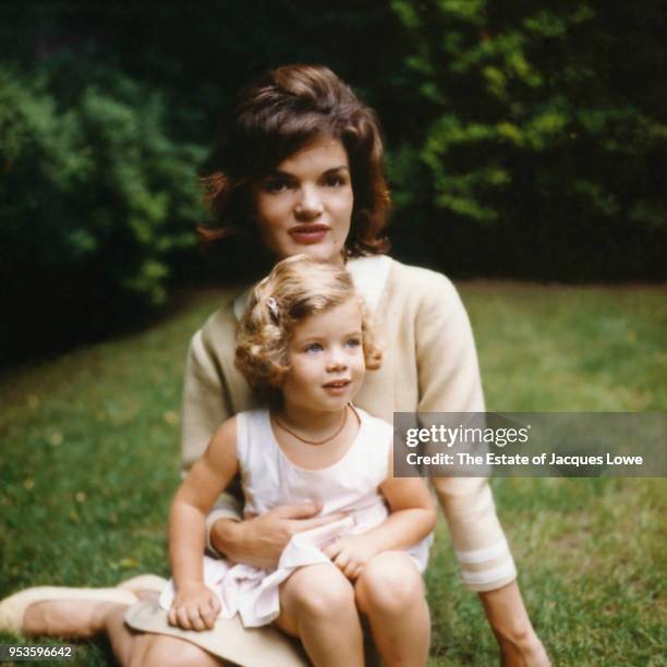 Portrait of Jacqueline Kennedy and her daughter, Caroline, as they sit together on the grass in garden of their Georgetown home , late 1950s or early...