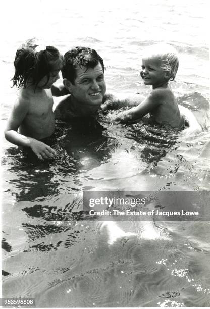 View of American politician US Senator Ted Kennedy as he swims with his children, Kara and Edward Jr, 1964.