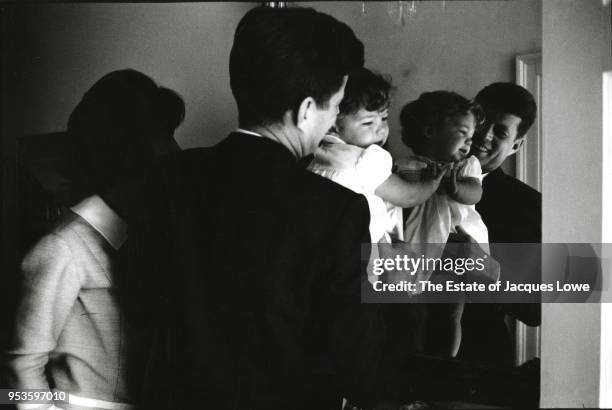 In their Georgetown home , US Senator John F Kennedy holds his daughter, Caroline, up to a large mirror as his wife, Jacqueline Kennedy , watches,...