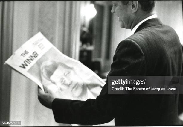 In his room at the Los Angeles Biltmore Hotel, American politician Senator John F Kennedy smiles as he holds a newspaper with the headline 'The...