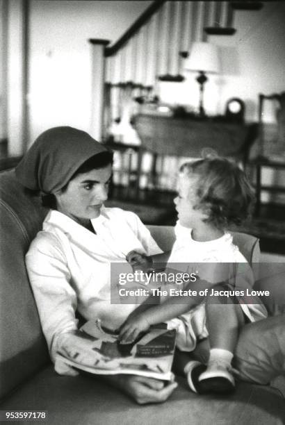 View of Jacqueline Kennedy on a sofa, her daughter Caroline on her lap, Hyannis Port, Massachusetts, August 1960. She holds an issue of Vogue magazine