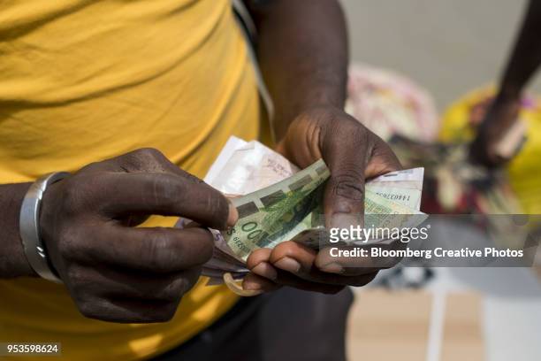 a man counts out west african cfa franc currency banknotes - franken stockfoto's en -beelden