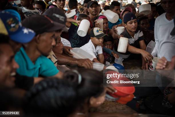 People wait to fill their containers with complimentary soup during a campaign rally for presidential candidate Javier Bertucci on International...