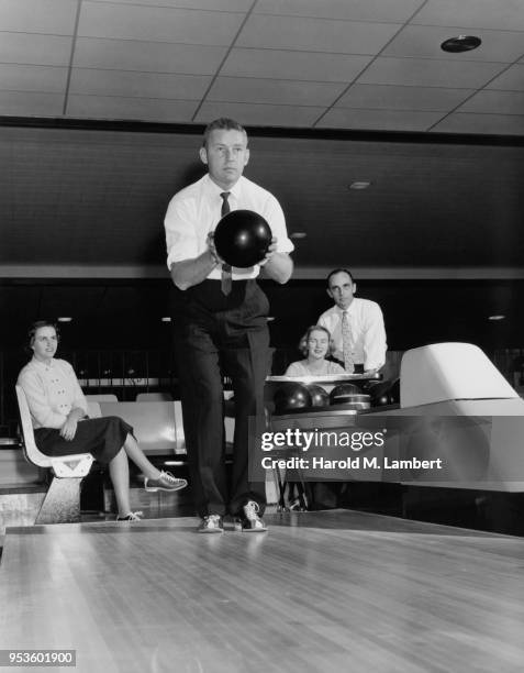 MID ADULT MAN AIMING TO THROW BALL IN TEN PIN BOWLING