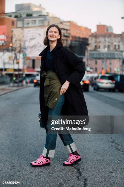 Model Daniela Kocianova wears a black jacket, a sweatshirt around the front of her waist, blue jeans with an exposed hem, and pink Supreme Nike ACG...