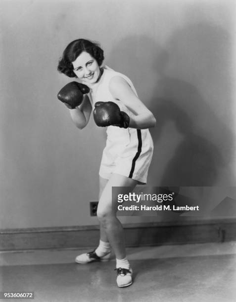 PORTRAIT OF ANGRY MID ADULT WOMAN WEARING BLACK BOXING GLOVES