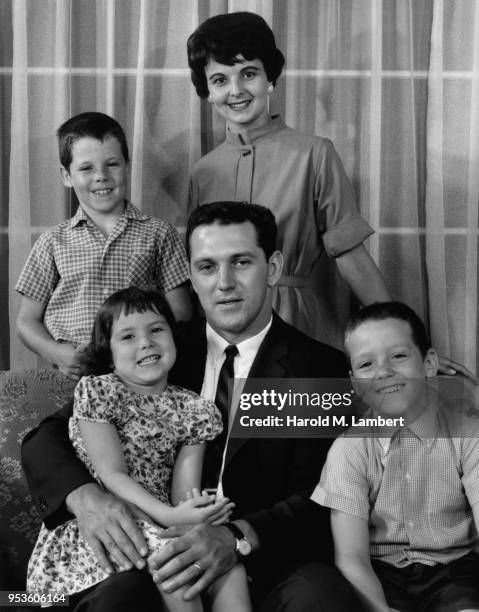 PORTRAIT OF FAMILY SITTING ON SOFA IN LIVING ROOM