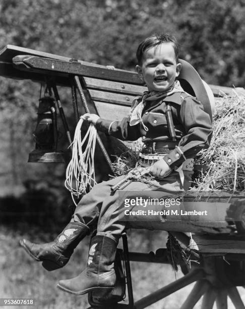 BOY WEARING SOLDIER UNIFORM WHILE SITTING ON OX CART