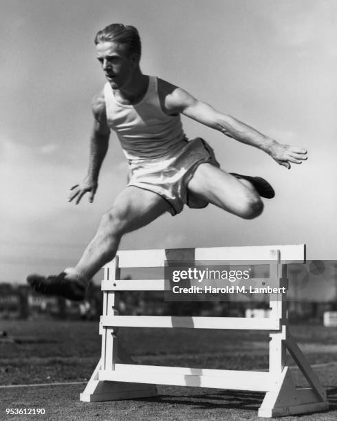 ATHLETE RUNNING AND JUMPING OVER HURDLE