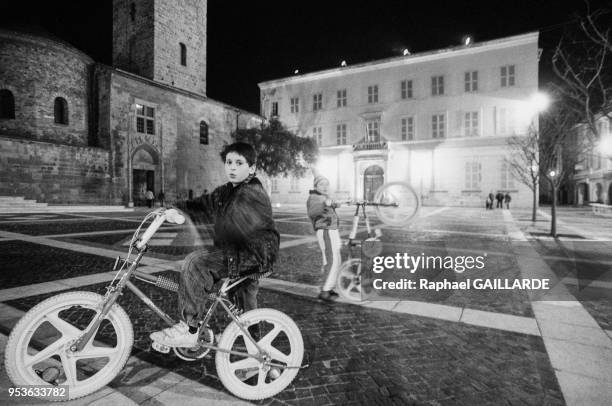 Jeunes garçons faisant du vélo sur la place de la mairie avec à gauche la cathédrale Saint-Léonce en décembre 1988 à Fréjus, Var.