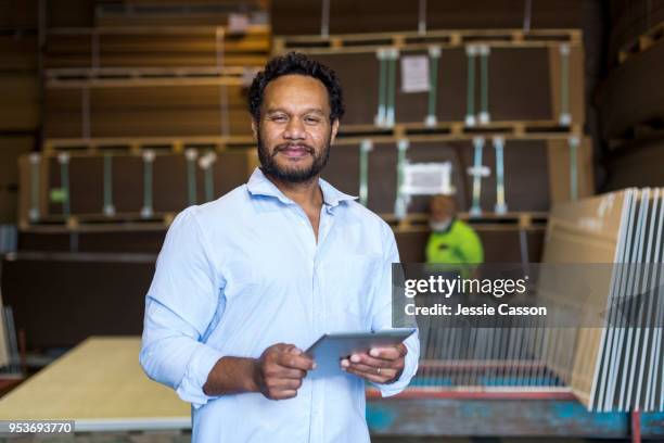 worker/supervisor stands with a tablet within factory warehouse - pacific islanders stockfoto's en -beelden