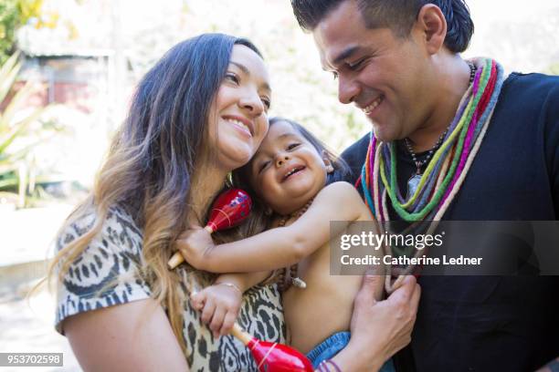 young parents smiling holding toddler outside in summer - catherine ledner foto e immagini stock