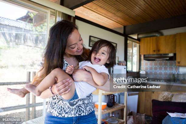 young mother and daughter playing inside and laughing - catherine ledner foto e immagini stock