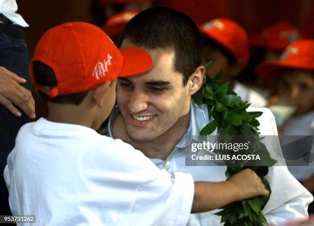 Juan Pablo Montoya Formula 1 pilot of the Williams stable, receives an olive-leaf crown 24 March 2001 from a child, in Bogota, Colombia. Montoya will...