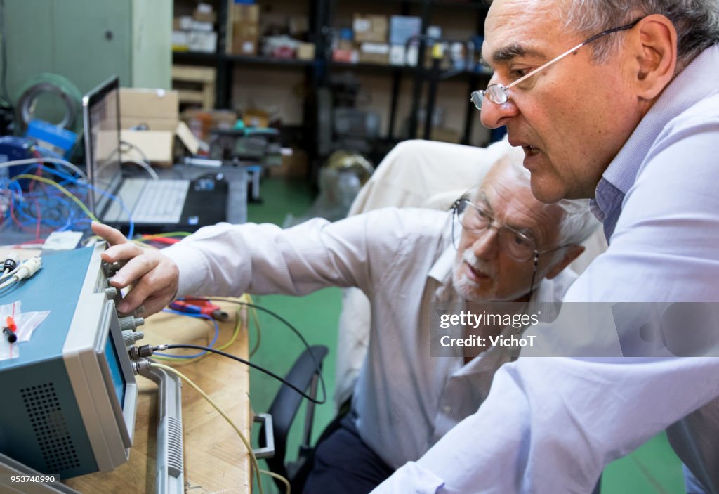 Two senior engineers working with oscilloscope