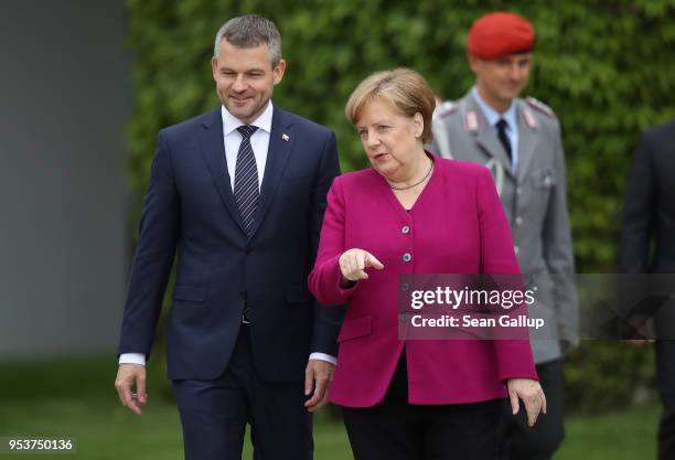 German Chancellor Angela Merkel and Slovak Prime Minister Peter Pellegrini prepare to review a guard of honor upon Pellegrini's arrival the...