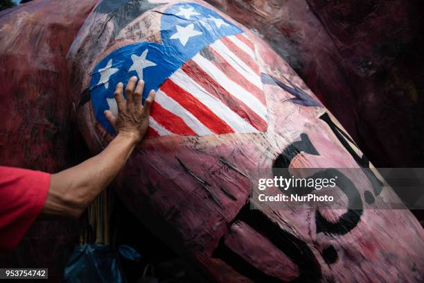 Hand of a Filipino worker is seen in an American flag painted on the effigy depicting President Rodrigo Duterte as a demon with metal hands before...