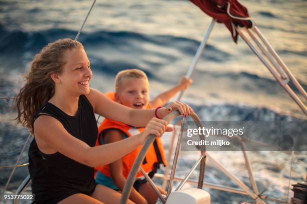 fille et garçon, profitant de vacances sur voilier - bateau à voile en famille photos et images de collection