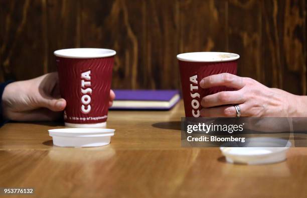 Customers hold disposable coffee cups in a Costa Coffee shop, operated by Whitbread Plc, in London, U.K., on Wednesday, May 2, 2018. Whitbread is...