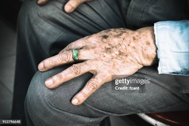 senior homme assis sur la chaise avec ses mains sur les genoux - hand on knee photos et images de collection