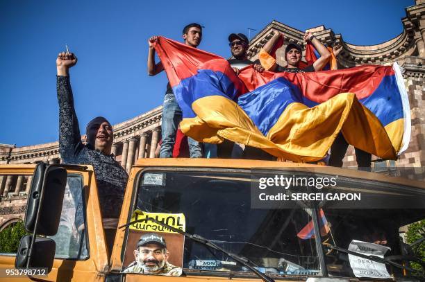 Protestors shout slogans and wave an Armenian national flag as they stand on a truck with a photograph of Armenian opposition leader Nikol Pashinyan,...