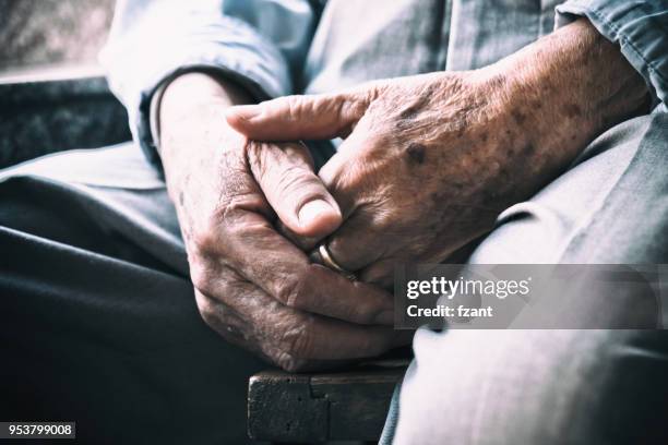 uomo anziano seduto su sedia e braccia incrociate - nocca foto e immagini stock