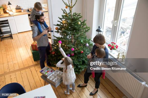 high angle view of young family decorating the christmas tree at home - kids advent stock pictures, royalty-free photos & images