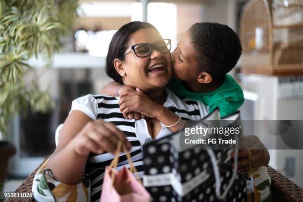 mother and son embracing and receiving gifts - mothers or children's day - offering stock pictures, royalty-free photos & images