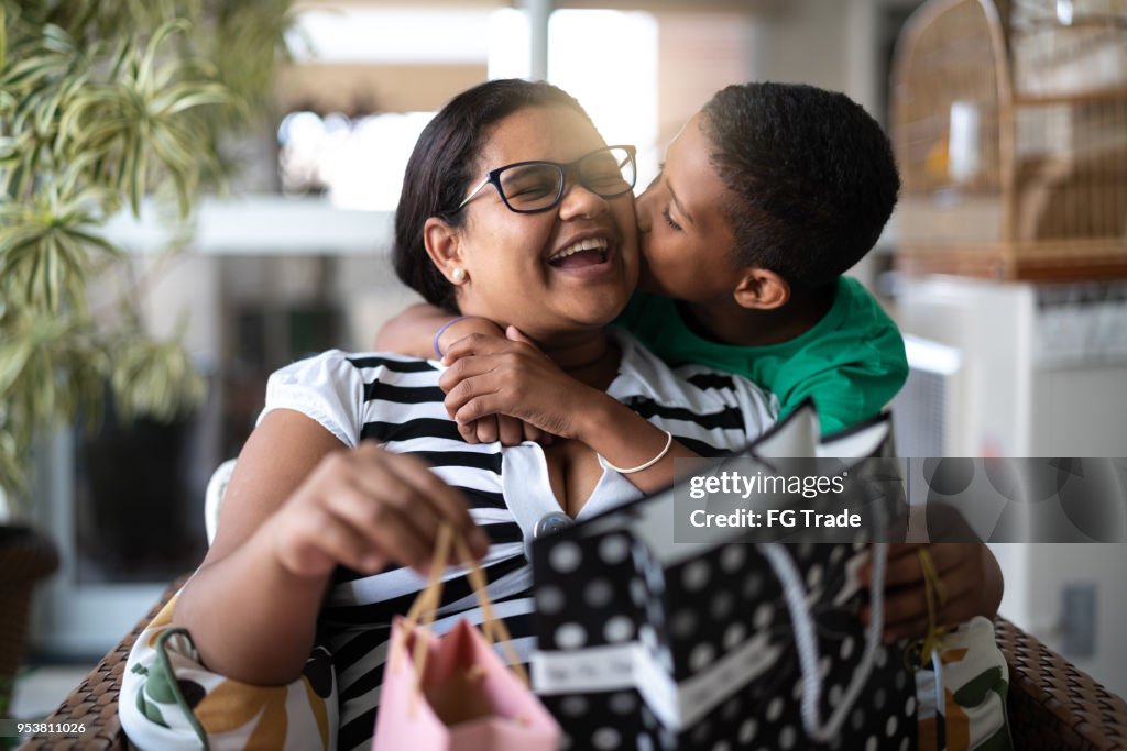 Mãe e filho, abraçando e recebendo presentes - dia das crianças ou mães