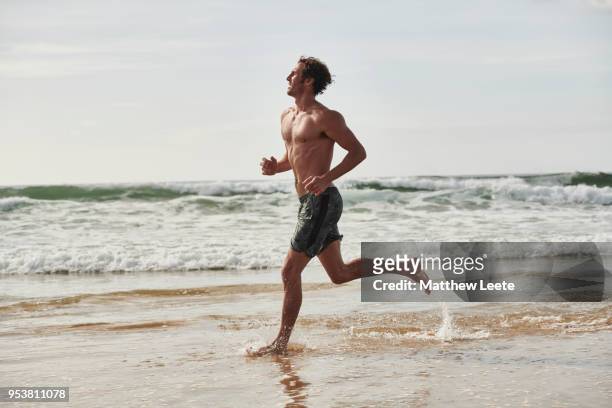 fit male running on beach - handsome man stock-fotos und bilder