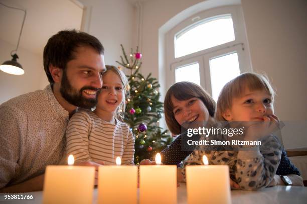 happy family sitting at table with four christmas candles - advent kerze stock-fotos und bilder