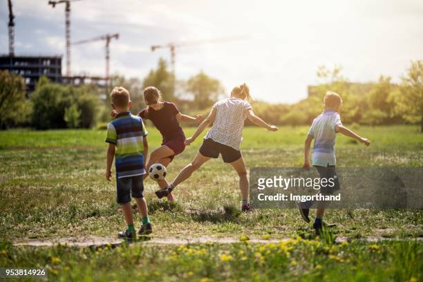 family having fun playing soccer outside the city - mother of all balls stock pictures, royalty-free photos & images