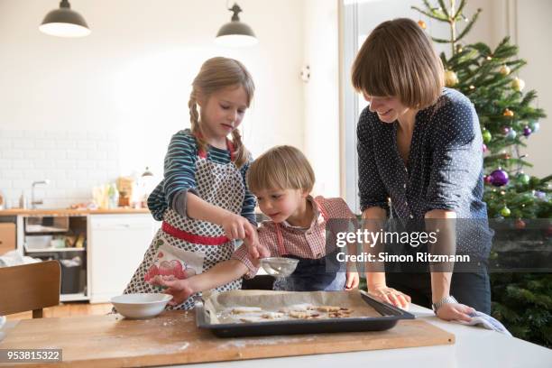 modern mother making cookies with daughter and son at christmas - powdered sugar stock-fotos und bilder